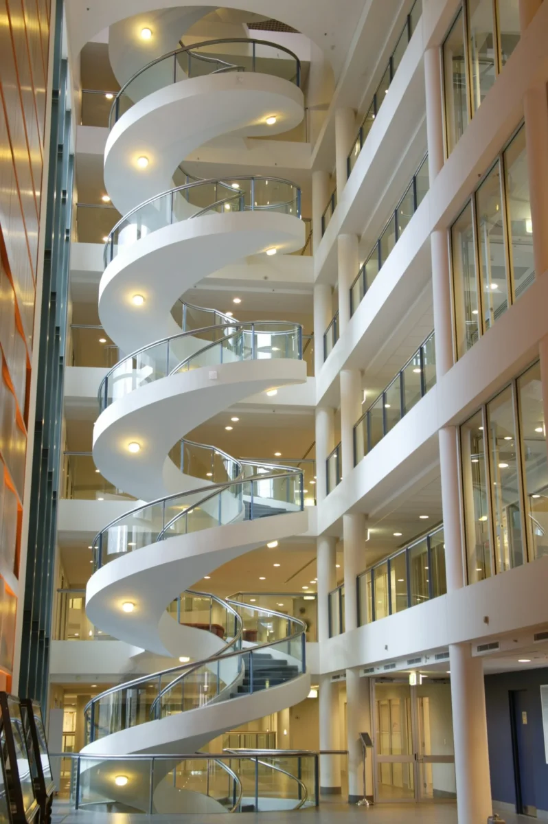 Elliptical Steel stair with bottom mount glass outer railing and inner wood cladded bannister